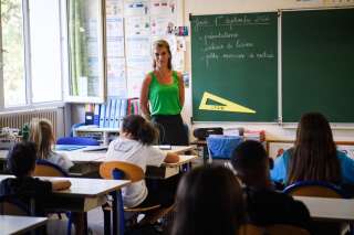 A teacher welcomes pupils in the classroom on the first day of the new academic at  