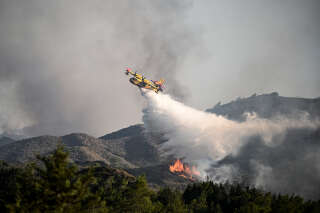 Un avion largue de l’eau au-dessus d’un feu de forêt près du village de Vati dans la partie sud de l’île grecque de Rhodes, à environ 70 km au sud-ouest de la capitale le 25 juillet 2023. Photo d’illustration.