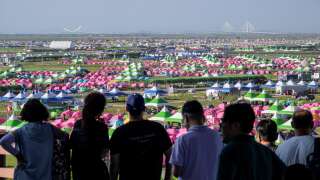 People visit a viewing platform to look at the campsite of the World Scout Jamboree in Buan, North Jeolla province on August 5, 2023. American and British scouts pulled out of the World Scout Jamboree in South Korea, citing scorching temperatures, as organisers weighed whether to cut short an event also reportedly plagued by dire campsite conditions. (Photo by ANTHONY WALLACE / AFP)