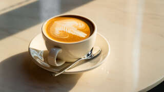 Latte fresco su un tavolo bianco, bevanda a base di caffè espresso e latte cotto a vapore.