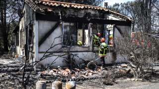 French firefighters work at a house destroyed by a wildfire in Saint-Andre, near Argeles-sur-Mer, southern France on August 15, 2023. French authorities evacuated more than 3,000 people from holiday campsites near the Spanish border on August 14 after a fire broke out, officials said. 