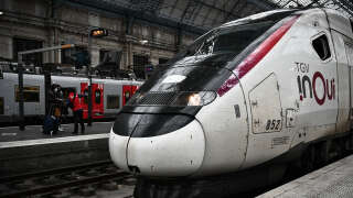 An SNCF personnel member attends passengers next to a TGV (high speed train) at the railway station in Bordeaux, southwestern France on November 25, 2021 on the day the metropolis of Bordeaux is expected to vote on a participation of 354 million euros to finance the extension of the Paris-Bordeaux LGV (high-speed rail line). The LGV project tears the majority between the socialists and the ecologists, led by the mayor of Bordeaux Pierre Hurmic, who prefer to this project an improvement of 