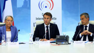 French President Emmanuel Macron addresses an intermninisterial crisis unit (Cellule interministerielle de crise - CIC) meeting next to French Prime Minister Elisabeth Borne (L) and French Interior and Overseas Minister Gerald Darmanin (R), after riots erupted for the third night in a row across the country following the death of Nahel, a 17-year-old teenager killed during a traffic stop in Nanterre by a French police officer, at the emergency crisis center of the Interior Ministry in Paris, France, June 30, 2023. (Photo by YVES HERMAN / POOL / AFP)
