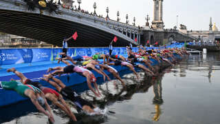 Triathlon athletes dive in the Seine river during the men's 2023 World Triathlon Olympic Games Test Event in Paris, on August 18, 2023. From August 17 to 20, 2023, Paris 2024 is organising four triathlon events to test several arrangements, such as the sports operations, one year before the Paris 2024 Olympic and Paralympic Games. The swim familiarisation event follows the cancellation on August 6 of the pre-Olympics test swimming competition due to excessive pollution which forced organisers to cancel the pre-Olympics event. (Photo by Bertrand GUAY / AFP)