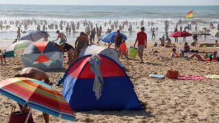 Vacationers shelf from the sun under a foldable tent on the beach of Lacanau, western France, on August 21, 2023, as France faces a heatwave. Tens of millions of people in France sweated through a late summer heatwave on August 21, 2023, with record temperatures expected in the wine-growing Rhone valley region and a forest fire also blazing in the southeast. (Photo by ROMAIN PERROCHEAU / AFP)