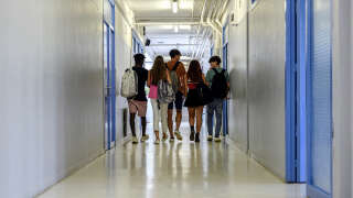 Rear view of a multiracial group of students walking in school corridor