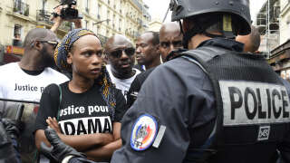 La sœur d’Adama Traore, Assa Traore, face à la police  anti-émeute français alors que des manifestants participent à une marche pour protester contre la mort de son frère devant la gare du Nord, à Paris, le 30 juillet 2016.
