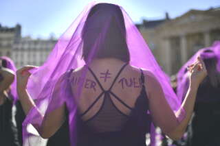 An activist wearing a veil with a slogan reading on her back 