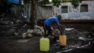 Une photo prise le 23 mai 2023 à Koungou où un habitant remplit des jerricanes d’eau potable près du bidonville du quartier « Talus 2 ».