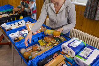 Medium shot of a food bank being run by volunteers at a community church in the North East of England. Focus on the food that has been donated lined up in crates on the table.
