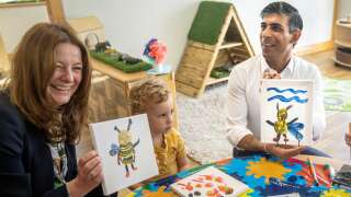 Britain's Prime Minister Rishi Sunak (C) and Britain's Education Secretary Gillian Keegan (L) hold images of bees they created during a visit to the Busy Bees nursery in Harrogate, North Yorkshire, on August 21, 2023. (Photo by Danny Lawson / POOL / AFP)
