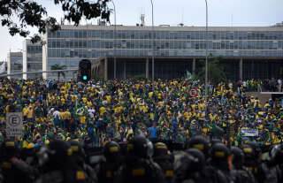 Supporters of Brazilian former President Jair Bolsonaro invading several governmental building are confronted by security forces (foreground) in Brasilia on January 8, 2023. Hundreds of supporters of Brazil's far-right ex-president Jair Bolsonaro broke through police barricades and stormed into Congress, the presidential palace and the Supreme Court Sunday, in a dramatic protest against President Luiz Inacio Lula da Silva's inauguration last week. (Photo by Ton MOLINA / AFP)