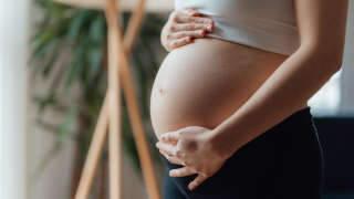 Side view close-up of pregnant woman touching her belly. Pregnancy health & wellbeing concept.
