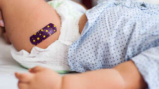 Close-up view of Southeast Asian baby boy with medical plaster after vaccination in the medical clinic