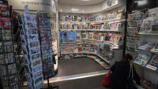 A woman looks for a newspaper in a kiosk on March 21, 2020, in Paris as a strict lockdown comes into in effect in France to stop the spread of COVID-19, caused by the novel coronavirus. A strict lockdown requiring most people in France to remain at home came into effect at midday on March 17, 2020, prohibiting all but essential outings in a bid to curb the coronavirus spread. The government has said tens of thousands of police will be patrolling streets and issuing fines of 135 euros ($150) for people without a written declaration justifying their reasons for being out (Photo by JOEL SAGET / AFP)