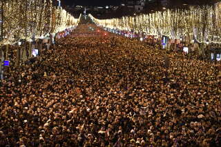 People gather on the Champs-Elysees as they wait for the New Year's Eve fireworks in Paris on December 31, 2022. (Photo by JULIEN DE ROSA / AFP)
