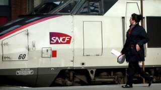 An employee of public railways service SNCF passes by a TGV train on April 2, 2018 at a train station in the northern French city of Lille, ahead of a planned strike. French rail unions will begin on April 2, 2018 a three-month rolling strike, two days out of every five, at state operator SNCF against planned reforms. (Photo by PHILIPPE HUGUEN / AFP)
