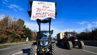 Un agriculteur manifeste avec  son tracteur indiquant « 400 euros par mois, pour 70 heures par semaine, Macron vient travailler à la ferme », dans le sud de la France, le 24 janvier 2024.