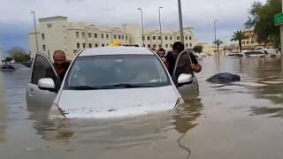 Dans cette capture vidéo de l’AFPTV, des personnes poussent une voiture bloquée dans une rue inondée de Dubaï, le 16 avril 2024. Dubaï, le centre financier du Moyen-Orient, a été paralysé par les pluies torrentielles qui ont provoqué des inondations dans les Émirats arabes unis et à Bahreïn et qui ont fait 18 morts à Oman les 14 et 15 avril.