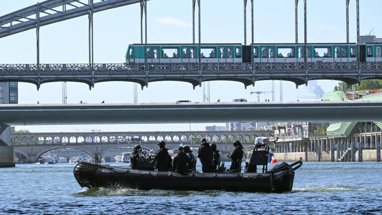 French police personnel manouver a Zodiac boat on the River Seine in Paris on July 17, 2023, to test "maneuvers", "distances", "duration" and "video capture" of the future opening ceremony of the Paris Olympics in 2024. For this mini-rehearsal, the total fleet is made up of 57 boats, 39 representing the delegations - slightly less than half as many as for the actual ceremony  in 2024 - and 18 others providing support (assistance, first aid) as well as Olympic Broadcasting Services (OBS), the Olympic TV broadcaster. (Photo by Bertrand GUAY / AFP)