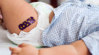Close-up view of Southeast Asian baby boy with medical plaster after vaccination in the medical clinic