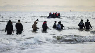 Migrants walks in the water to board a smuggler's boat on the beach of Gravelines, near Dunkirk, northern France on April 26, 2024, in an attempt to cross the English Channel. Five migrants, including a seven-year-old girl, died on April 23, 2024 trying to cross the Channel from France to Britain, local authorities said, just hours after Britain passed a controversial bill to deport asylum seekers to Rwanda. (Photo by Sameer Al-DOUMY / AFP)