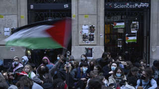 A protestor waves a Palestinian flag as they stage a sit-in in front of French riot policemen near the entrance of a Institute of Political Studies (Sciences Po Paris) building occupied by students, in Paris on April 26, 2024. Students occupied a new building at Sciences Po Paris, in support of Palestinians, a day after police evacuated another of the school's sites, echoing protest action at American universities. (Photo by JULIEN DE ROSA / AFP)