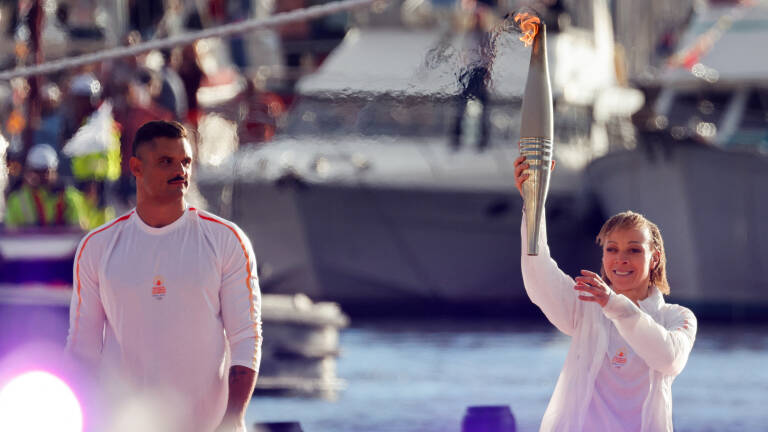 Nantenin Keïta (à droite) tient la flamme olympique aux côtés du nageur Florent Manaudou sur le Vieux-Port de Marseille, le 8 mai.