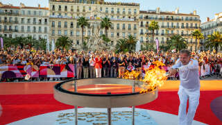This photo taken on May 10, 2024 and handout on May 11, 2024 by the Organizing Committee of the Paris 2024 Olympic and Paralympic Games (COJOP) shows French actor Charles Berling holding the Olympic Torch as part of the Olympic and Paralympic Torch Relays, in the streets of Toulon, southeastern France, ahead of the Paris 2024 Olympic and Paralympic Games. (Photo by Cedric Michel / ORGANIZING COMMITTEE OF THE PARIS 2024 OLYMPIC AND PARALYMPIC GAMES / AFP) / RESTRICTED TO EDITORIAL USE - MANDATORY CREDIT 