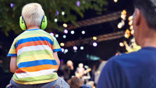 Rearview shot of a young boy sitting on his father's shoulders at a music concert