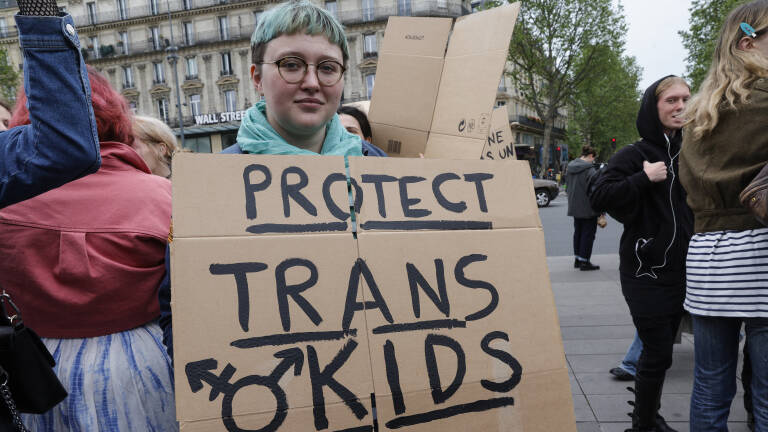 A protester holds a placard reading "Protect trans kids" during a demonstration against transphobia and transphobic attacks at the Place de la Republique in Paris, on May 5, 2024. (Photo by Geoffroy VAN DER HASSELT / AFP)