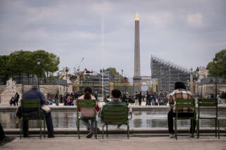 People sit at the Jardin des Tuileries garden in front of the construction site of La Concorde Urban Parc site for the upcoming Paris 2024 Olympic Games, with the Obelisque de Louxor in the background, on April 26, 2024 in central Paris. The La Concorde Urban Park will host street skateboarding, BMX freestyle, 3×3 basketball and Breaking Olympic events that will take place in the four arenas set up at central Paris' Place de La Concorde. (Photo by Guillaume BAPTISTE / AFP)