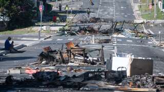 A street blocked by debris and burnt out items is seen following overnight unrest in the Magenta district of Noumea, France's Pacific territory of New Caledonia, on May 18, 2024. Hundreds of French security personnel tried to restore order in the Pacific island territory of New Caledonia on May 18, after a fifth night of riots, looting and unrest. (Photo by Delphine Mayeur / AFP)